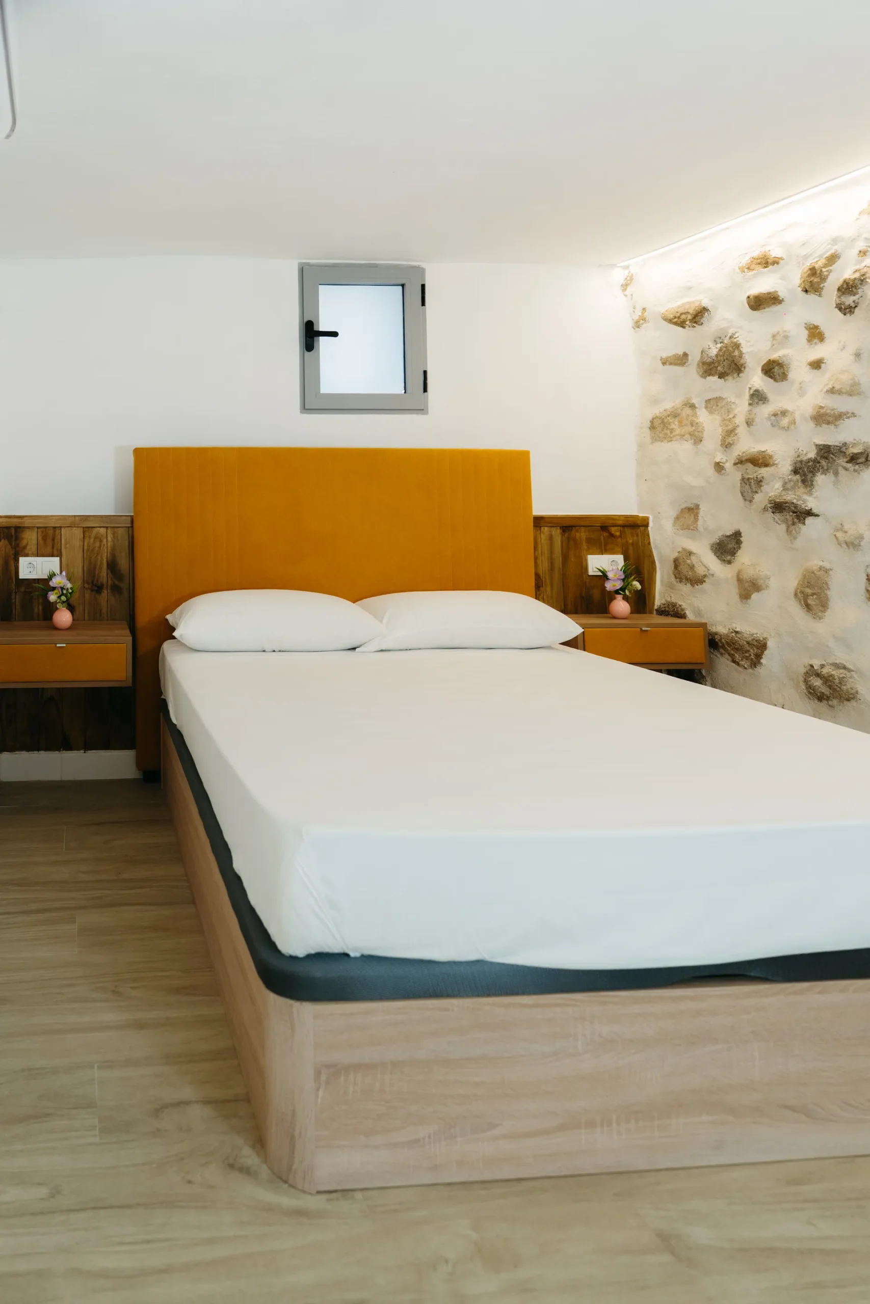 Courbu - Dormitorio con cabecero y pared de piedra